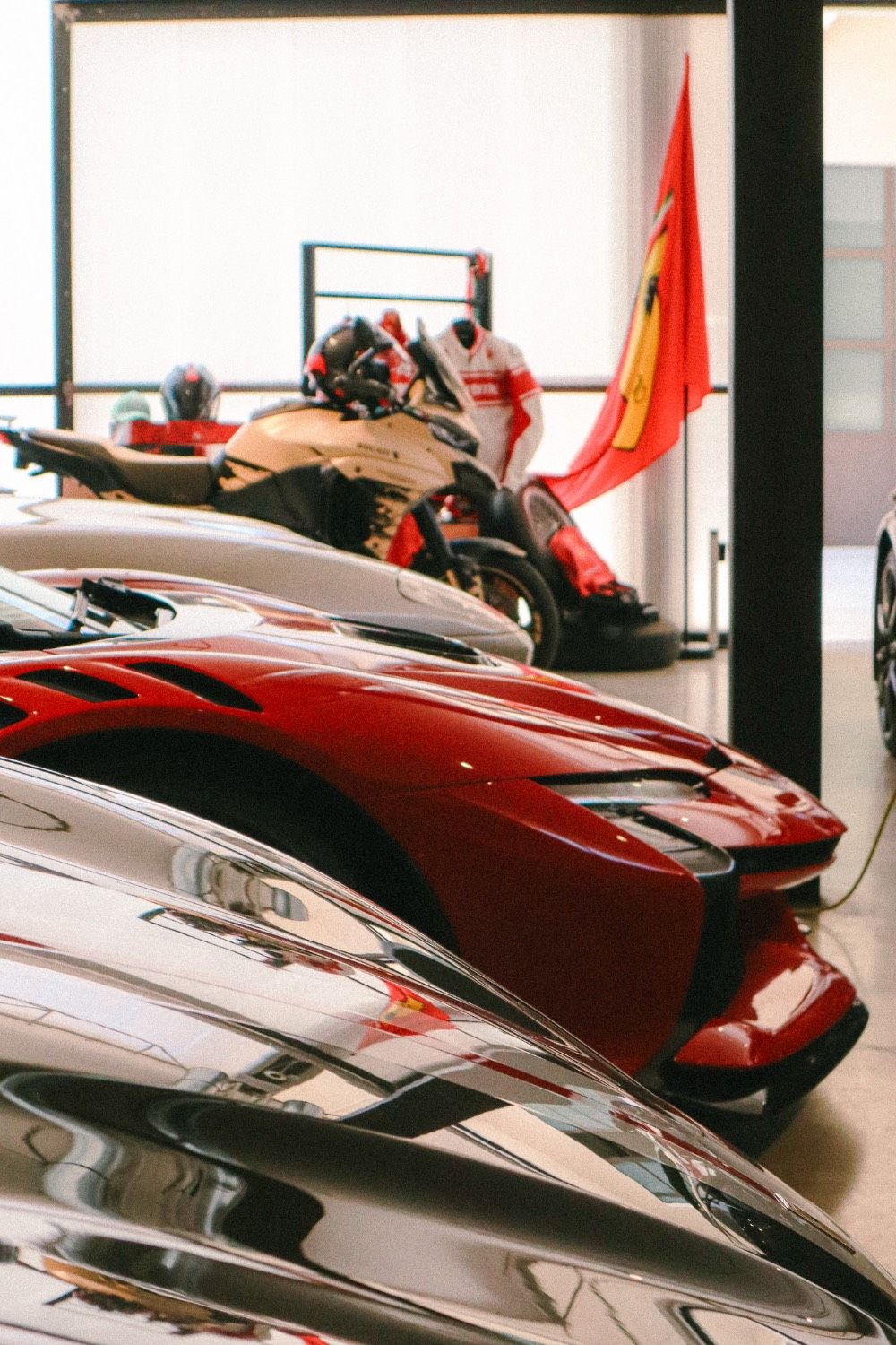 Close-up of a red sports car and motorcycles in a showroom