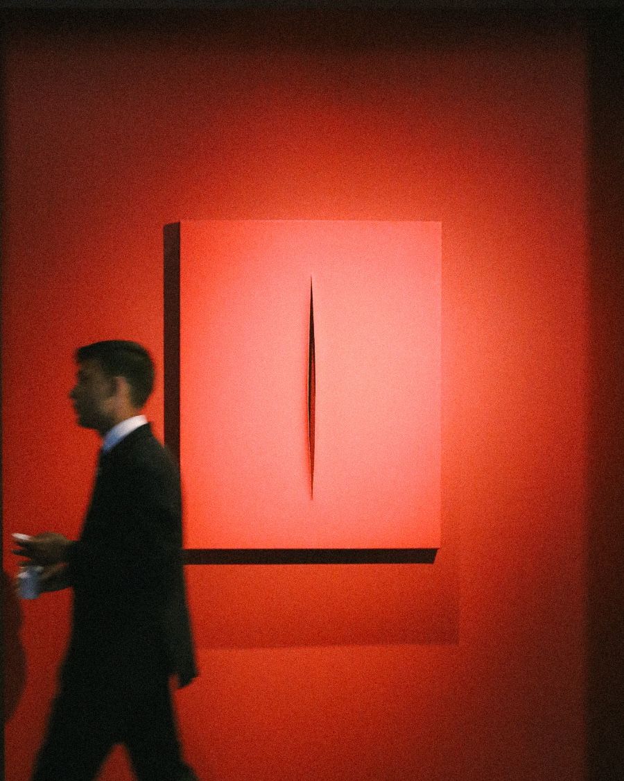 Man walking past a red slashed canvas artwork