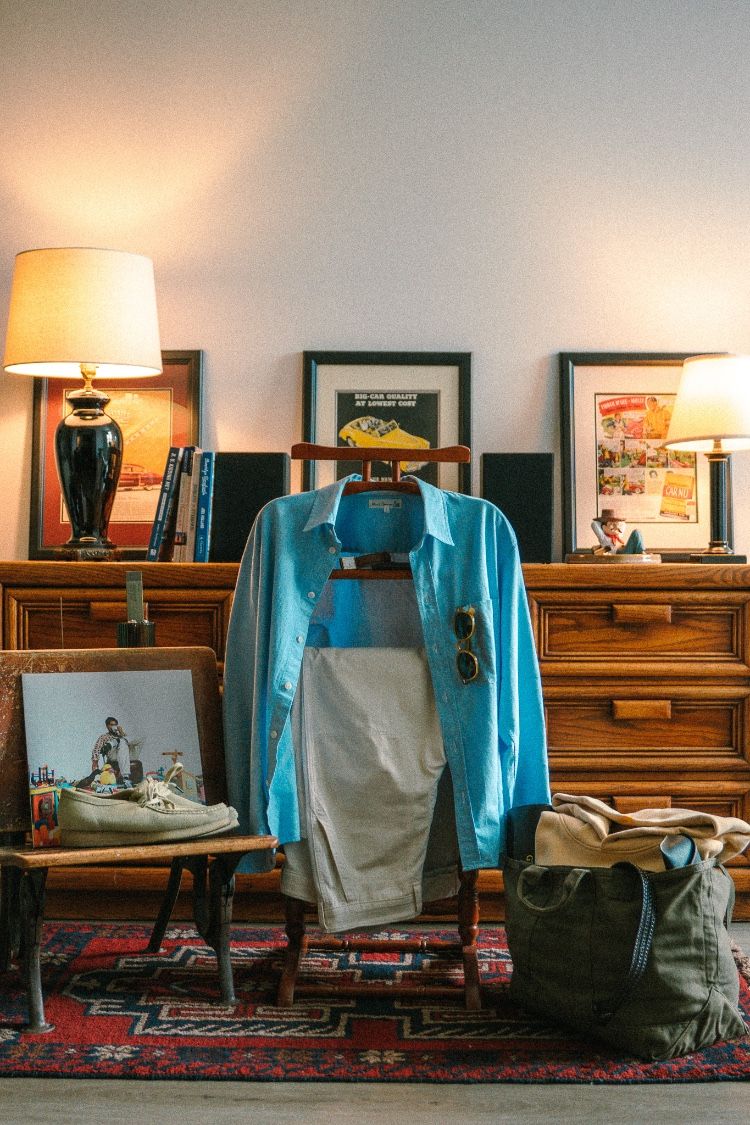 Blue shirt and packed bag styled on a vintage dresser