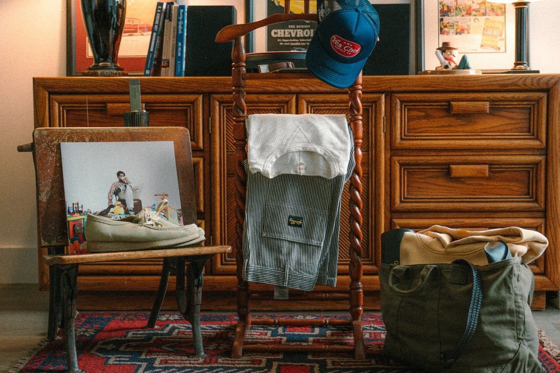 Wide view of clothes and packed bag styled on a vintage dresser